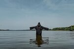 man-black-robe-hands-outstretched-stands-middle-lake-warm-weather-his-gaze-focused-water-12555...jpg
